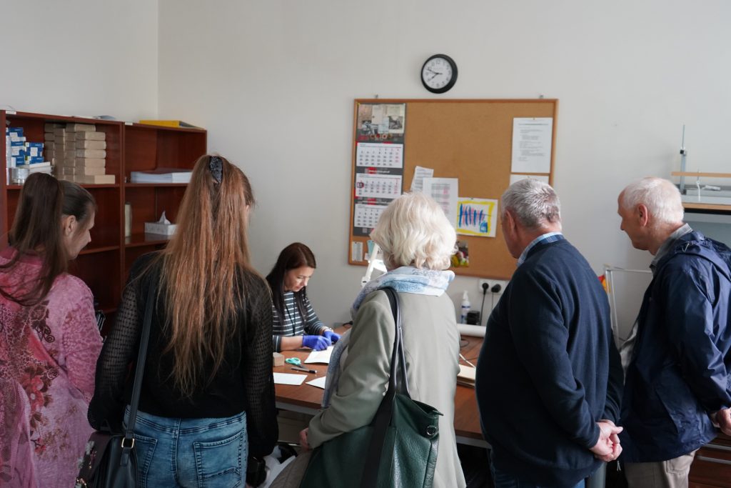 Zwiedzanie pracowni konserwacji. Kobieta pokazuje podklejanie akt.