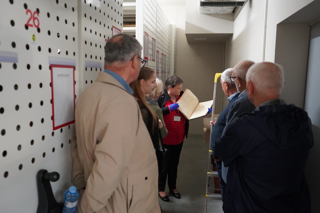 Zwiedzanie magazynów archiwalnych. Kobieta pokazuje akta.