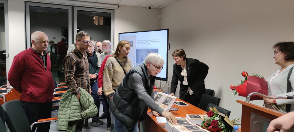 Uczestniczy spotkania odbierają książki. 